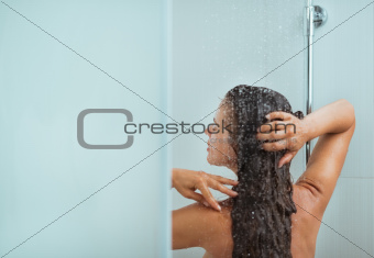Woman with long hair taking shower. Rear view