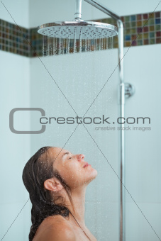 Woman with long hair taking shower under water jet
