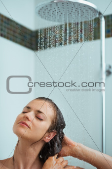 Relaxed woman taking shower under water jet