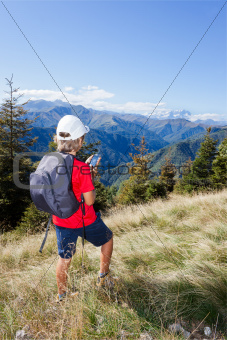 Young boy standing along a mountain path using a  smartphone