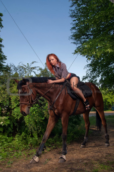 woman with red hair sitting on a horse