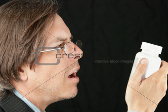 Casual Businessman Wearing Reading Glasses Trying To Read Pill B