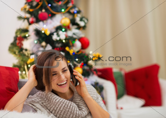 Happy woman near Christmas tree speaking mobile