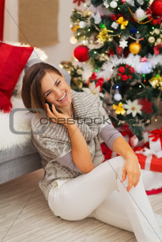 Happy woman near Christmas tree having phone call