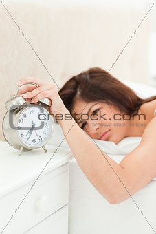 An alarm clock showing the time being silenced by a woman lying 
