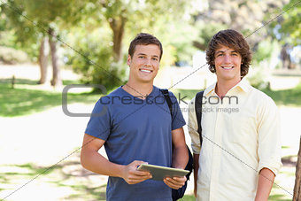 Close-up of two smiling male students with a touch pad