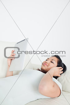Woman lying on a couch with headphones on and holding a tactile 