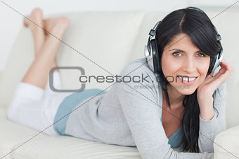 Woman smiling with headphones on while lying on a sofa