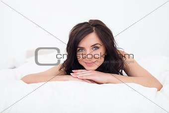 Brunette woman lying on her white duvet