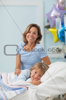 Child lying on a bed next to his mother