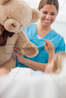 Happy nurse holding a teddy bear