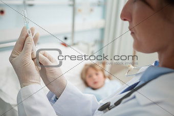 Doctor preparing a syringe next to a child