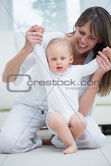 Mother raising arms of her baby