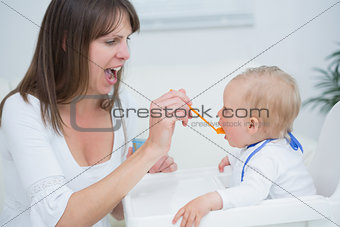 Mother feeding a baby while opening her mouth