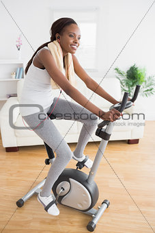 Black woman doing exercise bike while smiling