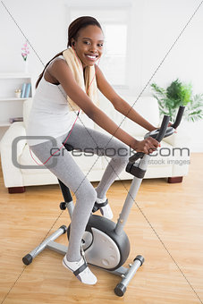 Black woman doing exercise bike with headphones