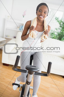 Black woman doing exercise bike while wearing a towel