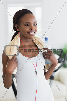 Black woman wearing a towel while holding a bottle