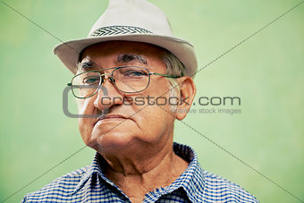 Portrait of serious old man with hat looking at camera 