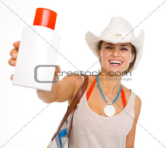 Happy young beach woman in hat showing sun block creme
