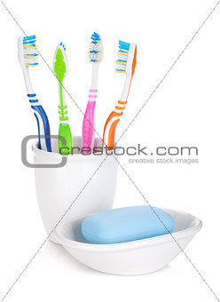 Four colorful toothbrushes and soap