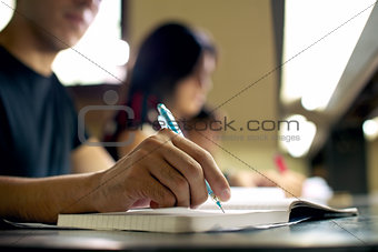 young man doing homework and studying in college library