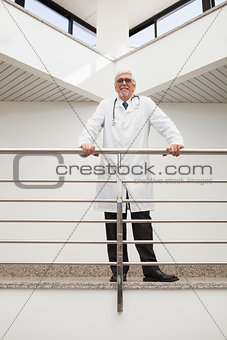 Happy doctor leans against rail