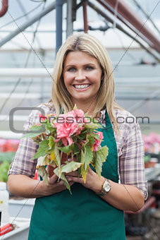 Blonde woman holding a flower working in garden center