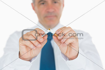 Businessman breaking a cigarette