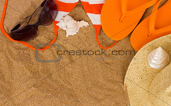 orange sandals  and sunbathing accessories at sand