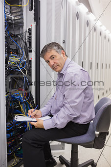 Man checking servers and writing on clipboard