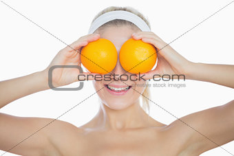 Happy woman holding oranges in front of eyes