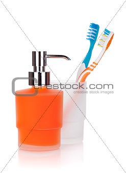 Two colorful toothbrushes and liquid soap