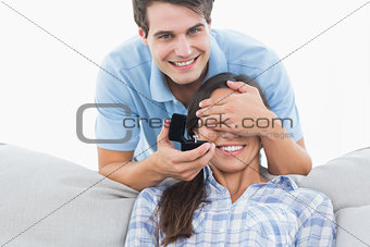 Man hiding his girlfriends eyes and offering her an engagement ring