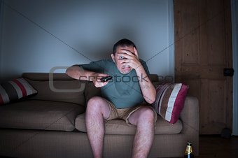 man covering face watching tv