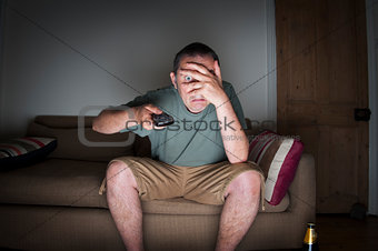 man covering his eyes watching tv
