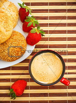 coffee, buns and strawberries on table
