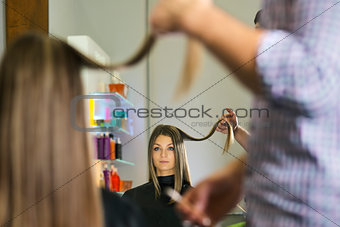 woman in hairdresser shop cutting long hair 