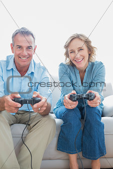 Smiling couple playing video games together on the couch