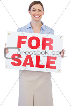 Cheerful estate agent posing with for sale sign