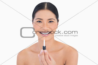 Smiling attractive model holding lip gloss