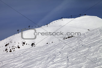 Off-piste slope and ropeway against blue sky