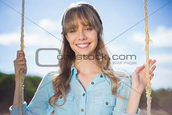 Cheerful young model relaxing sitting on swing