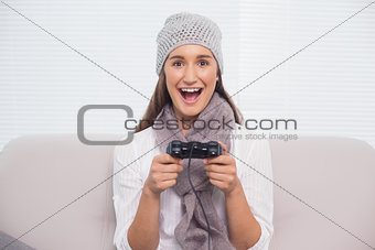 Smiling brunette with winter hat on playing video games