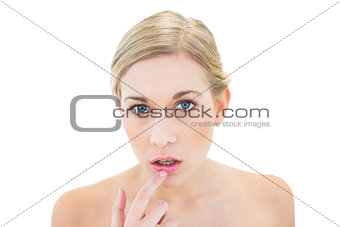 Stressed young blonde woman pointing her lip with her finger