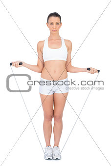 Serious woman in sportswear exercising with skipping rope