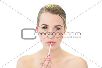 Attractive blonde applying lip gloss
