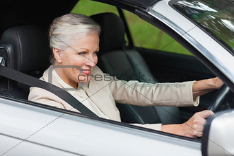 Smiling businesswoman driving classy car