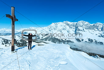 Tourist near the cross on winter mountain top
