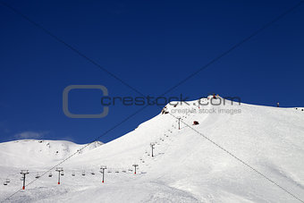 Ski slope with ropeway at sun winter day